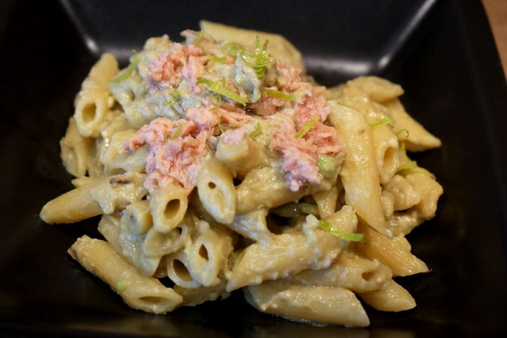 Primo piano della pasta fredda con crema di avocado, tonno e scorza di limone grattugiata